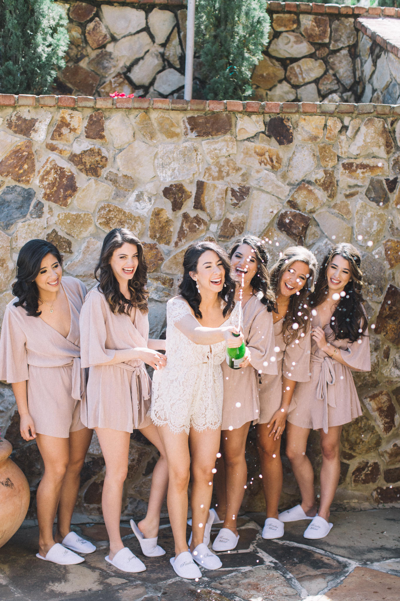 bride with bridesmaids popping champagne